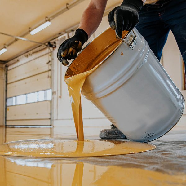 Worker applying a yellow epoxy resin bucket on floor. Worker applying a yellow epoxy resin bucket on floor.Construction series
