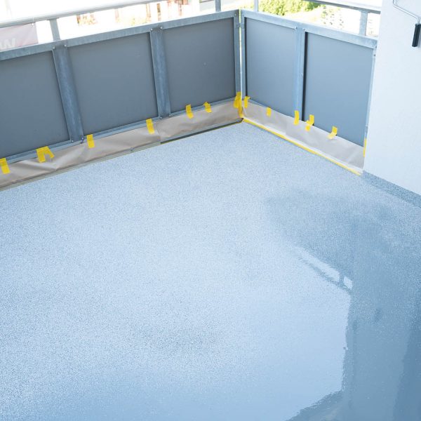 construction worker renovates balcony floor and spreads chip flo A construction worker renovates balcony floor and spreads chip floor covering on resin and glue coating before applaying water sealant